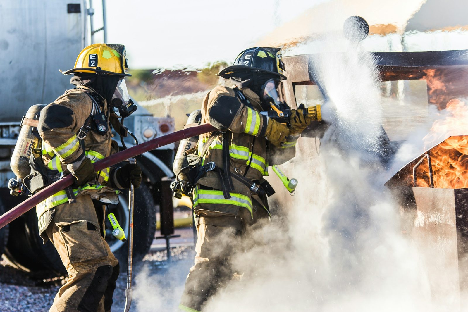 Two firefighters in turnout gear working at a fire scene