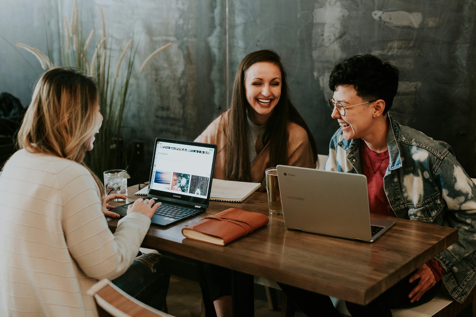 Three students working together at a table with laptops